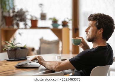 Happy young man in his moment of relaxation turns off the laptop holding a cup of hot milk coffee with his hands, latte art, in his favorite cafe, he enjoys the aroma of coffee and it gives him energy - Powered by Shutterstock