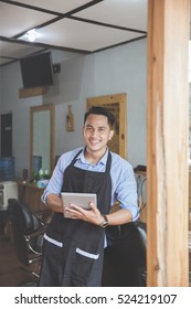 happy young man holding tablet pc while sitting at barbershop. business marketing with digital technology - Shutterstock ID 524219107