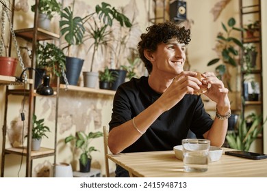happy young man holding tofu burger and looking away while smiling in vegan cafe, enjoyment - Powered by Shutterstock
