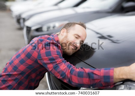 A Happy young man hugging his car outside of garage shop