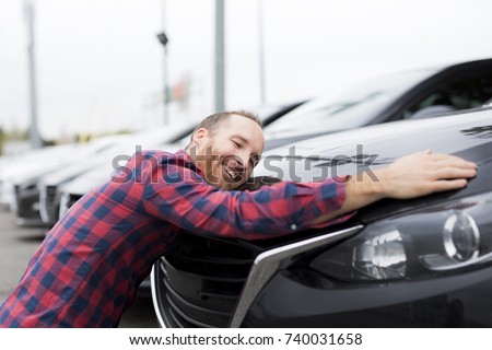 A Happy young man hugging his car outside of garage shop