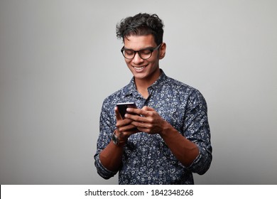 Happy Young Man Of Indian Origin Looking At His Mobile Phone