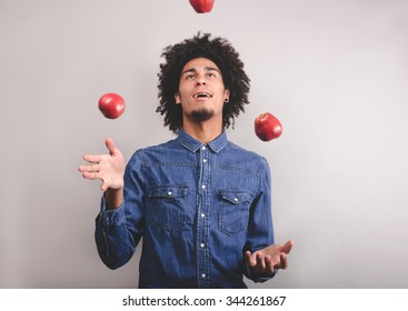 Happy young man juggling with apples on a white background