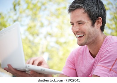 Happy Young Man With A Laptop Outdoors