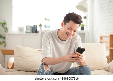 happy young man  looking at cell phone in living room at home