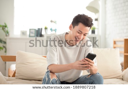 happy young man  looking at cell phone in living room at home