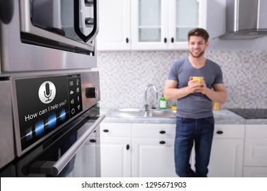 Happy Young Man Looking At Oven With Voice Recognition Function In Kitchen - Powered by Shutterstock