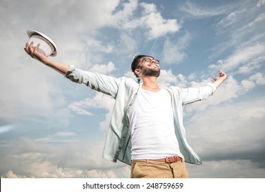 Happy Young Man Looking Up To The Sky Holding Both Hands In The Air, Enjoying The Sun.