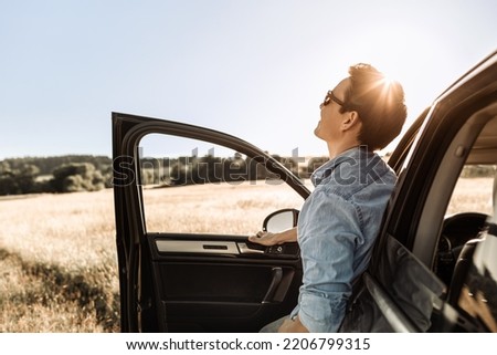 Happy young man looking up to the sky on a road trip getaway. Feel good lifestyle , freedom in nature concept. 