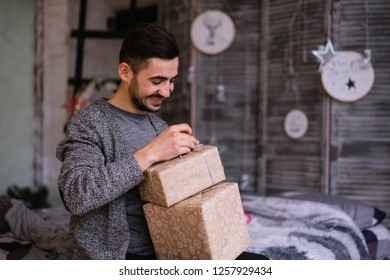 Happy Young Man Opening Christmas Gift At Home. Happy Atmosphere. Surpised