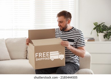 Happy Young Man Opening Parcel At Home. Free Shipping