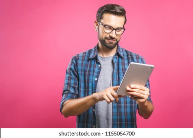 Happy young man in plaid shirt standing and using tablet over pink background - Powered by Shutterstock