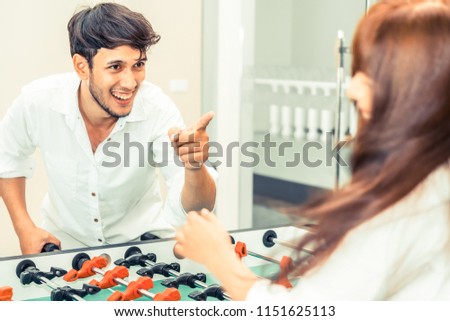 Happy young man playing foosball table soccer with girlfriend. Couple recreation and lifestyle.