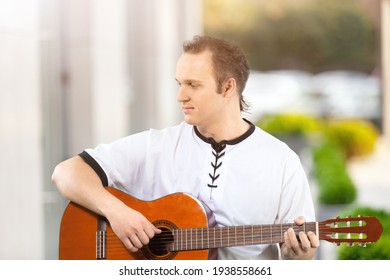 Happy Young Man Playing Guitar Outside The Home