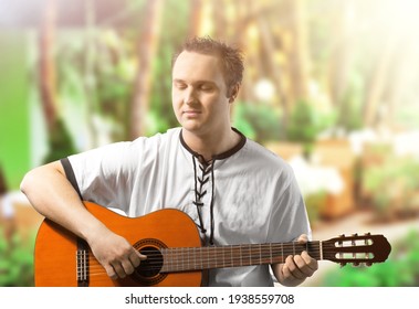 Happy Young Man Playing Guitar Outside The Home