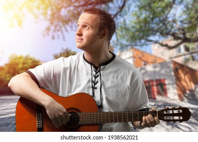 Happy Young Man Playing Guitar Outside The Home