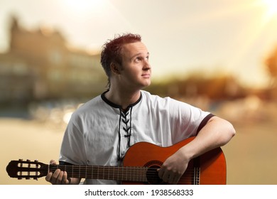 Happy Young Man Playing Guitar Outside The Home