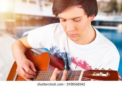 Happy Young Man Playing Guitar Outside The Home