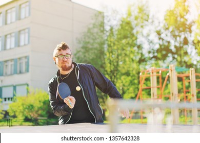 Happy young man playing ping pong table tennis with ball and paddle outdoors Healthy college sport and people activity, youth lifestyle, fun rest concept. Tournament game player outside in hostel park