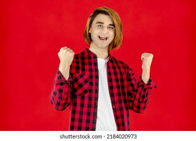 Happy Young Man Prep Student With Long Hair. Portrait Of A Guy On A Red Background.