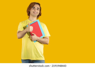 Happy Young Man Prep Student With Long Hair. Portrait Of A Guy With Thumbs Up On A Yellow Background.