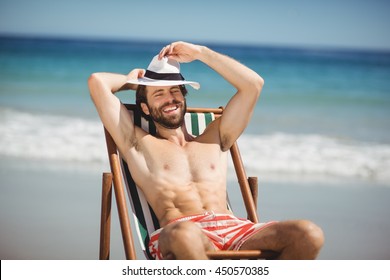 Happy Young Man Relaxing On Armchair At Beach