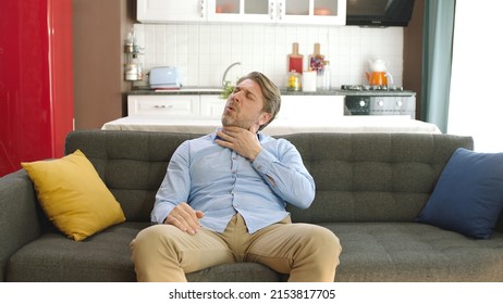 Happy Young Man Sitting Alone On Sofa At Home. Concept Of Happy Male At Home.Thoughtful Serious Young Man Alone Sitting Alone On Sofa At Home. Bored And Pensive Male Alone At Home Looking At Camera. 