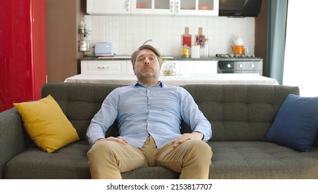 Happy Young Man Sitting Alone On Sofa At Home. Concept Of Happy Male At Home.Thoughtful Serious Young Man Alone Sitting Alone On Sofa At Home. Bored And Pensive Male Alone At Home Looking At Camera. 