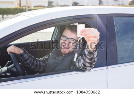 Happy young man sitting in car holding car keys
