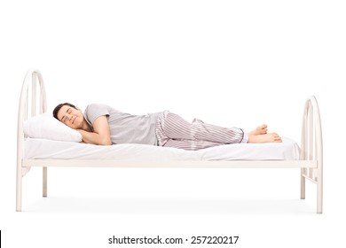 Happy young man sleeping in a bed isolated on white background