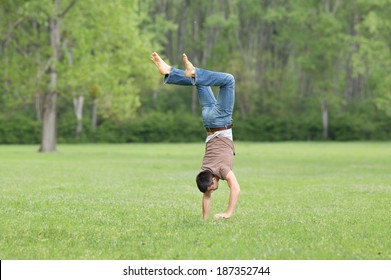 Happy young man standing upside down on grass