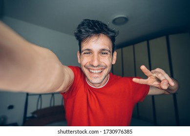 Happy Young Man Takes Selfie Portrait At Home Indoor. Guy Smiling Looking At The Camera.