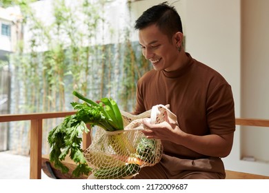 Happy young man taking out groceries he bought at local market - Powered by Shutterstock