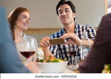 Happy Young Man Taking Picture Of Food. Friend Capturing Memories By Using Camera. 
Young Friend Enjoying Lunch.
