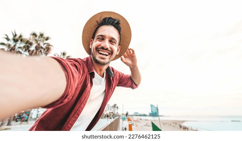 Happy young man taking selfie with smart mobile phone outdoors - Cheerful tourist having fun on summer vacation - Travel blogger, people and summertime holidays concept