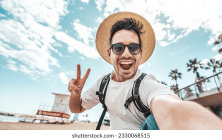 Happy young man taking selfie pic with smart mobile phone device outside - Smiling male tourist laughing at camera on summertime vacation - Summer holidays and modern technology life style concept - Powered by Shutterstock