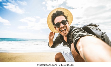Happy young man taking selfie at the beach side - Smiling guy looking at camera outside - Summer vacations and technology concept  - Powered by Shutterstock