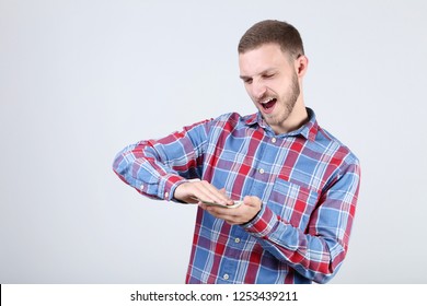 Happy young man throwing dollar banknotes on grey background