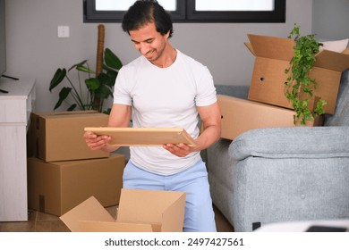 Happy young man unpacking a photo frame in his new apartment - Powered by Shutterstock