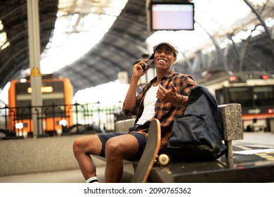 Happy young man waiting for the train. African man waiting in a subway. Man talking to the phone