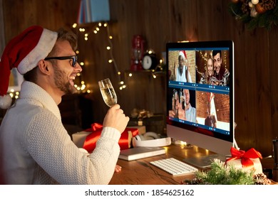 Happy young man wears santa hat drinking champagne talking meeting friends on virtual zoom video call celebrate New Year party in holiday distance online conference chat together on computer at home. - Powered by Shutterstock