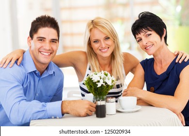 happy young man with wife and mother-in-law in cafe