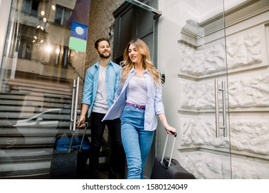 Happy young man and woman leaving hotel with luggage - Powered by Shutterstock