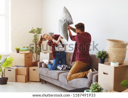 a happy young married couple moves to new apartment and laughing,  jump, fight pillows

