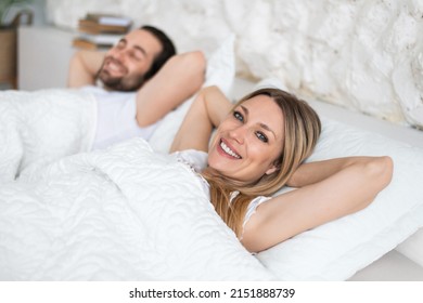 Happy Young Married Couple Relaxing On Soft Pillows In Bed, Enjoying Lazy Weekend Morning At Home, Copy Space. Millennial Caucasian Woman And Her Boyfriend Waking Up Together At Hotel