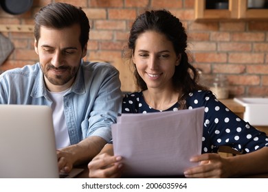 Happy young married couple reviewing loan, mortgage agreement, analyzing fee schedule, planning costs and family budget. Husband and wife using laptop and reading documents together