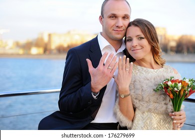 Happy young married couple showing wedding rings during boat trip