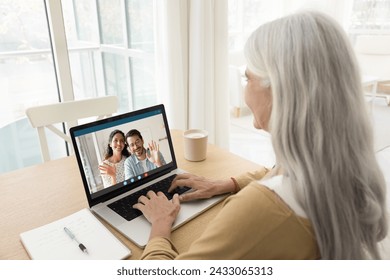 Happy young married couple talking to senior mom on video call, waving hands from laptop screen, smiling, enjoying online family meeting, distant Internet communication - Powered by Shutterstock