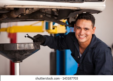 Happy Young Mechanic Draining Engine Oil At An Auto Shop For An Oil Change