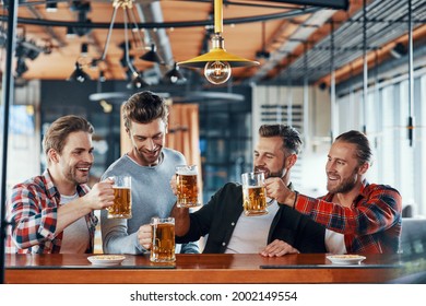 Happy young men in casual clothing toasting each other with beer and smiling - Powered by Shutterstock